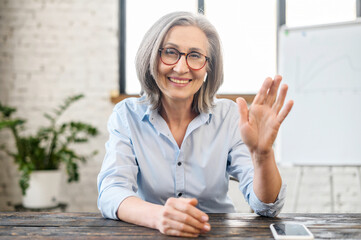 Video chat with a smiling senior elderly business woman. Webcam view of charming aged coworker,...