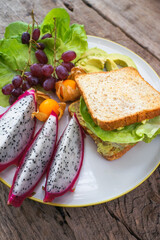 Wheat bread and Avocado fillet with salad and Fresh fruit. Healthy food, diet lunch concept. Top view on wooden background