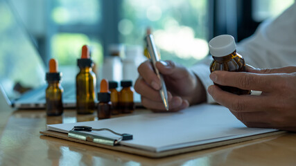 The doctor held a bottle of medicine and gave the medicine to the patient. The doctor sat at the desk in the office.