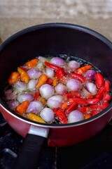 Shallots and chilies are fried in a stainless pan, before being mixed with other cooking ingredients