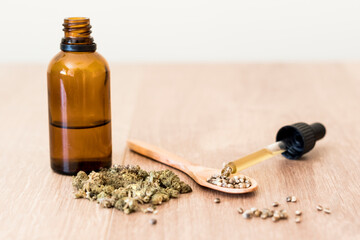 CBD oil with dispenser, seeds and hemp flowers selective focus