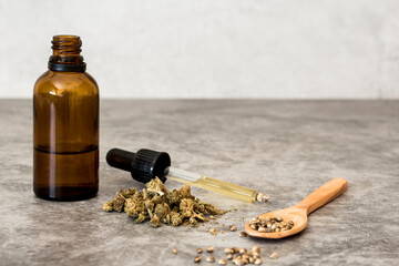 CBD oil with dispenser, seeds and hemp flowers selective focus