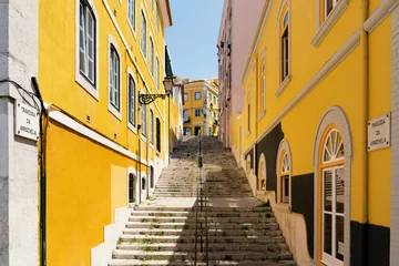 Fotobehang Smal steegje Staircase alley in the old town of Lisbon with yellow picturesque house facades.  © Anna