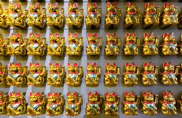 A wall with many Lucky Cats Maneki-Neko front view.