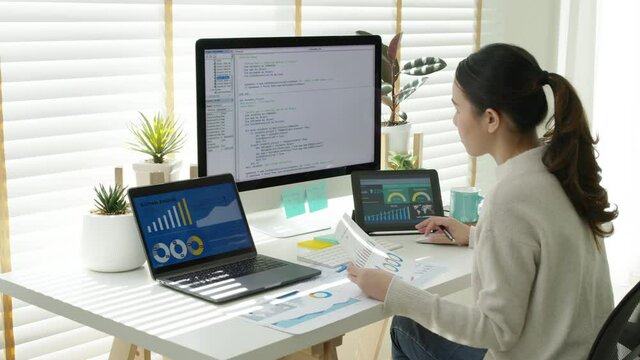 Back rear view of young asian woman, freelance data scientist work remotely at home coding programing on Big data mining, AI data engineering, IT Technician Works on Artificial Intelligence Project.