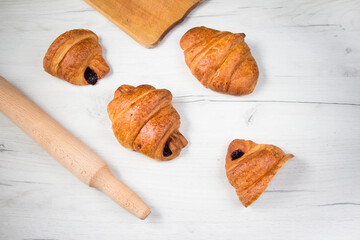 croissants lay on white wooden table near rolling pin and cutting board. Top view, flat lay