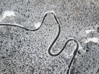 Aerial view of a road winding through snow covered forest