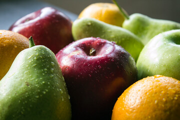 Organic fruits close up photo. Fresh juicy apples and pears on a table. Water drops on fa fruit skin. Healthy eating concept. 