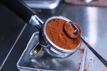 Close-up, coffee holder on the kitchen scale, ground coffee beans in the filter, Coffee in the spoon, background blurred