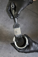 Man holding black paint and brush. Home renovation concept. Close up photo of working man. 