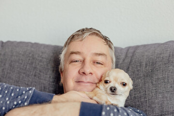 Caucasian man 47 years old hugging with love at his mini beige chihuahua dog