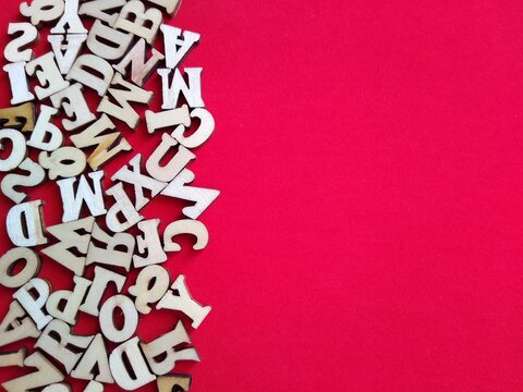 wooden letters of the alphabet scattered on a red background with space for text. High quality photo