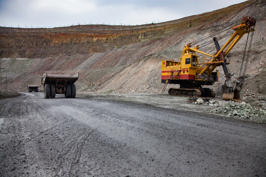 Rudny, Kazakhstan - May 14, 2012: Open-pit Mining Iron Ore In Quarry. Big Yellow Electric Excavator And Two Caterpillar Quarry Trucks On Quarry Road.