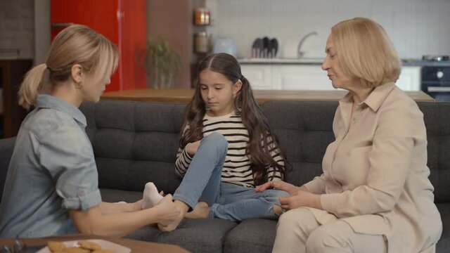 Portrait of happy family laughing together, loving each other.Young mother and grandmother dress their little daughters in socks. Portrait of happy family laughing together, loving each other.