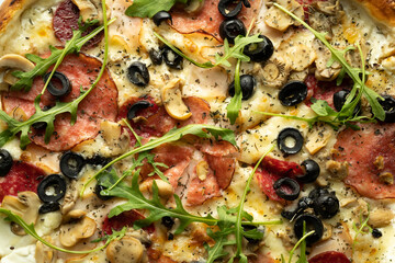 Top view of pizza with olives, salami, arugula and cheese in a box. Delivery of orders from a pizzeria.