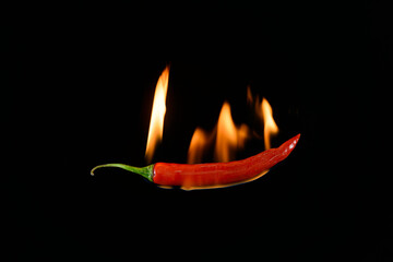 Red hot chili pepper on black background with flame