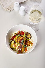 Turkey fillet baked with grilled vegetables and saffron. A glass of white wine. Delicious and healthy gourmet dinner recipes. Mediterranean Kitchen. Food still life. White background. Top view