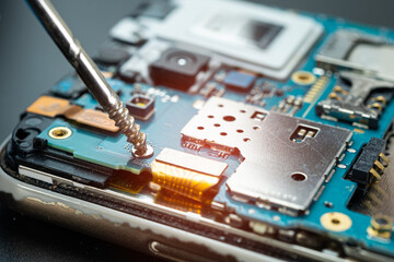 Technician repairing inside of mobile phone by soldering iron. Integrated Circuit. the concept of...