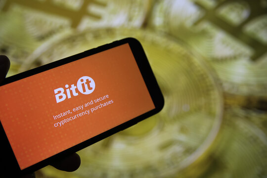 Viersen, Germany - February 9. 2021: Closeup of mobile phone screen with logo of bitit lettering trading platform, blurred bitcoins background