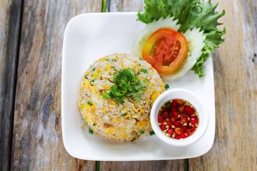 Fried Rice with egg in the white dish on wooden table