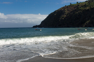 Boats in the turquoise sea with gentle waves with mountain and blue sky in the background in Chichiriviche de la Costa, Vargas Venezuela
