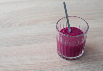 Blueberry cocktail (smoothie) in a glass with a metal spoon on a wooden table