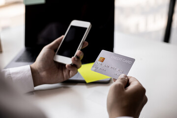 A man with a credit card and a smartphone is filling out his credit card information in order to pay for online purchases ordered from online shopping sites. Concept of using a credit card.