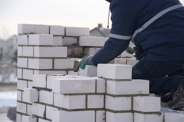 Bricklayer working on a construction site, laying concrete blocks, close-up.