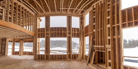 Interior view of a cathedral ceiling living room skeleton structure hole for windows, fire place at a new American real estate development construction site
