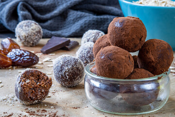 Close up on healthy energy protein balls with dates, oats, peanut butter and dark chocolate. Homemade gluten free truffle bites covered with cocoa powder. Vegan, vegetarian raw appetizer or food snack