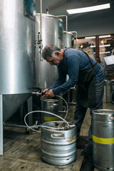 brewer is pouring beer in barrels .