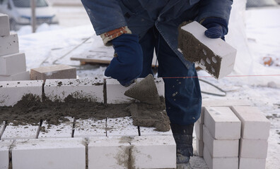 The builder puts the bricks in the cement mortar, will make the masonry wall of the new building.