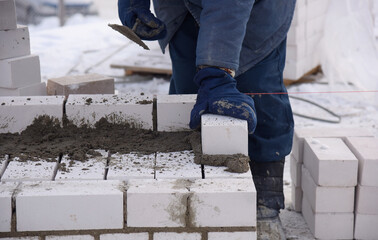 Mason lays bricks set in cement, making the masonry walls,the construction of the house.