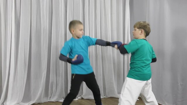 In multi-colored T-shirts and pads on their arms, two athletes train paired exercises