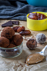 Healthy energy protein balls with dates, oats, peanut butter and dark chocolate. Homemade gluten free truffle bites covered with cocoa powder or almonds. Vegan raw appetizer or small snack. Side view.