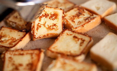 Yummy square-shaped  croutons fried in a pan. Homemade food, breakfast. White bread in egg fried in a pan with butter. Home kitchen. Croutons flip with a fork.
