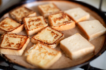 Yummy square-shaped  croutons fried in a pan. Homemade food, breakfast. White bread in egg fried in a pan with butter. Home kitchen, gas stove.