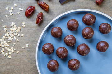 Healthy energy protein balls with dates, oats, peanut butter and dark chocolate placed on a plate. Homemade gluten free truffle bites with no bake. Vegan and vegetarian raw appetizer or food snack.
