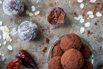 Healthy energy protein balls with dates, oats, peanut butter and dark chocolate. Homemade gluten free truffle bites covered with cocoa powder or almonds. Vegan raw appetizer or small snack. Top view.
