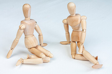 two wooden mannequins sitting together on white background