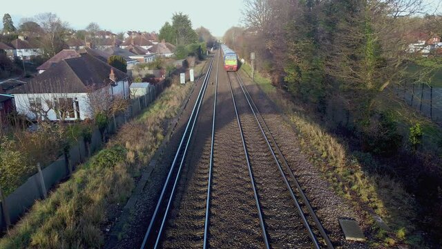 A fast green yellow colour commuter passenger train in UK traveling on a two track line just close to the station Epsom / London on a sunny day.