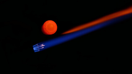 A Lampworkers blue and red torch flame as he pulls the formed molten glass out of it 