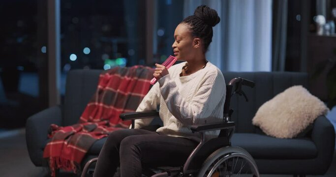 Young beautiful afro woman disabled girl singing happy positive song laughing hard enjoying evening swinging in wheechair around house.