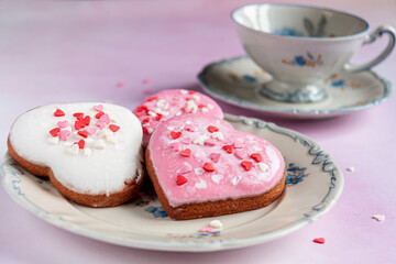 three heart-shaped gingerbreads on a blue-and-white porcelain saucer and a blue-and-white porcelain cup on watercolor background