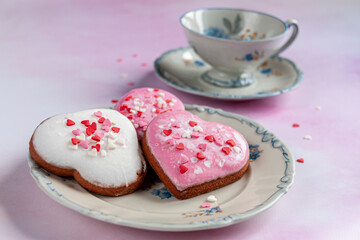 three heart-shaped gingerbreads on a blue-and-white porcelain saucer and a blue-and-white porcelain cup on watercolor background