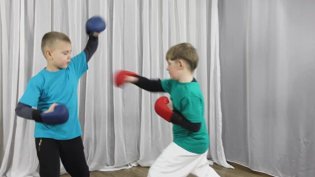 Two athletes in multi-colored T-shirts and pads on their arms practice sparring