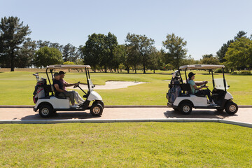 Two caucasian senior couples driving golf buggy on golf course talking and smiling