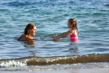 Mamma e figlia in costume da bagno giocano e si divertono mentre si fanno il bagno al mare