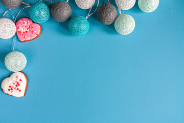 a garland of white, gray and blue balls and pink and white heart-shaped gingerbreads on blue background
