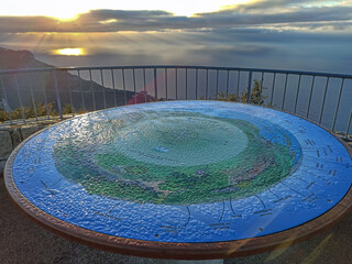 Naklejka premium Table d'orientation recouverte de rosée dans les lueurs du soleil levant en montagne